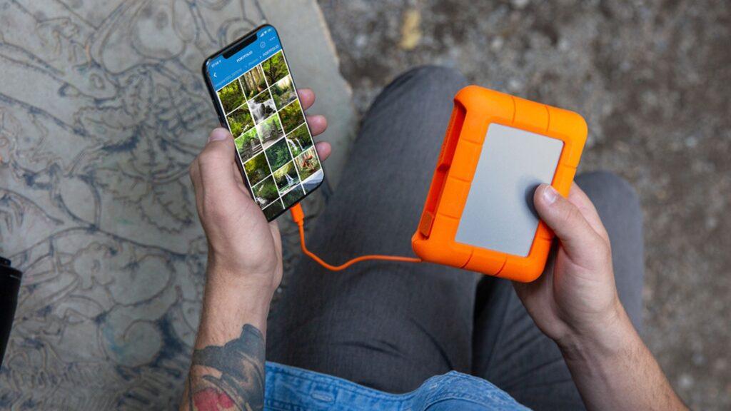 A filmmaker using a LaCie Rugged portable hard drive to transfer footage from their smartphone