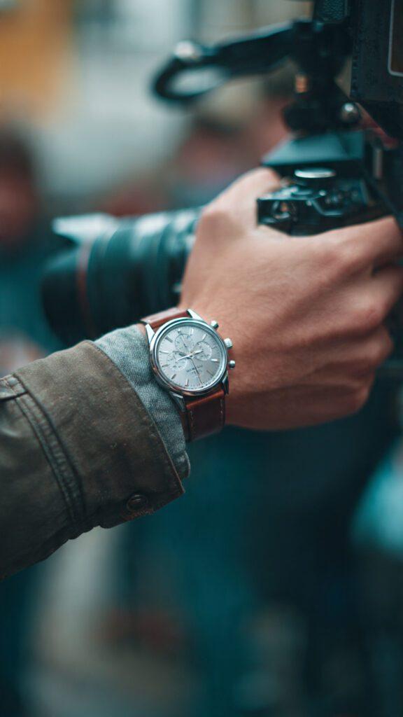 Filmmaker wearing durable field watch while operating camera on documentary shoot