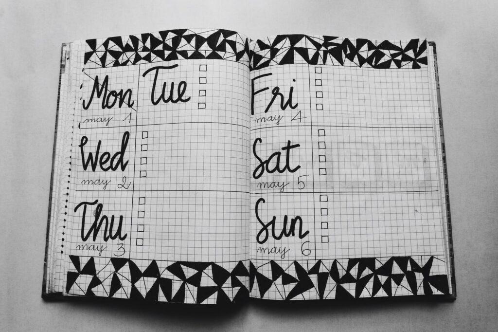 daily routine- white and black weekly planner on gray surface