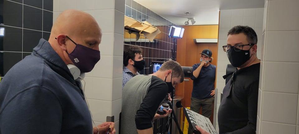 Low-budget short film - Film crew at work in an airport terminal departure area, featuring actors, director, and assistant director coordinating a scene.