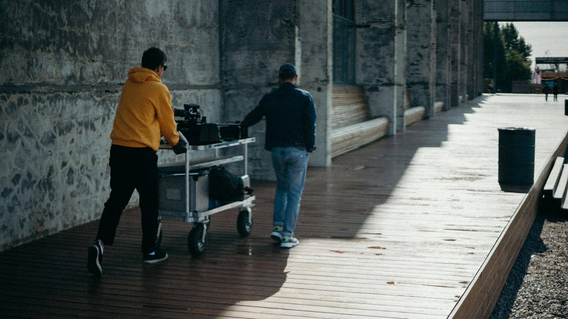 two person pulling gray cart