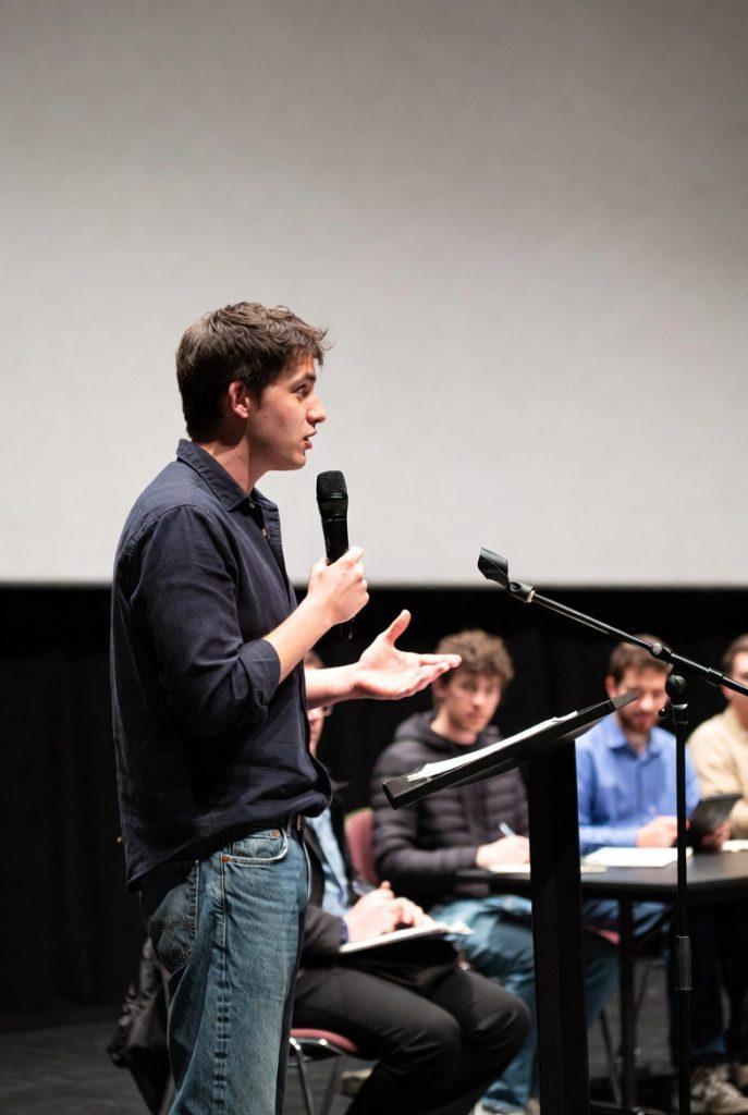 person answering questions in front of a juror answering the hard questions for a movie pitching contest