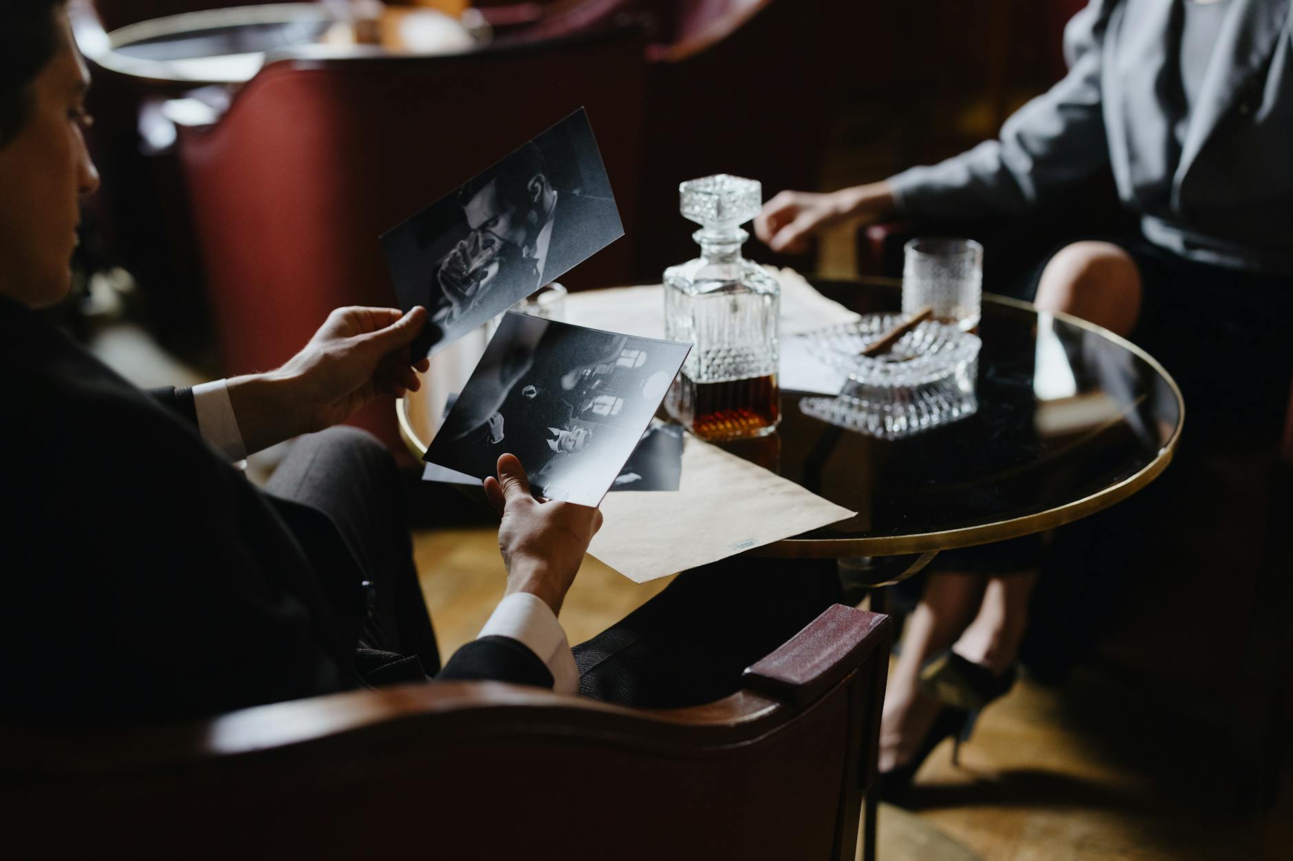man in black suit looking at photographs