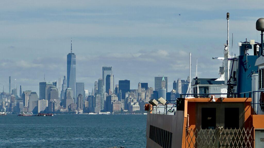 The Staten Island Ferry crossing New York Harbor with the iconic Manhattan skyline in the background.