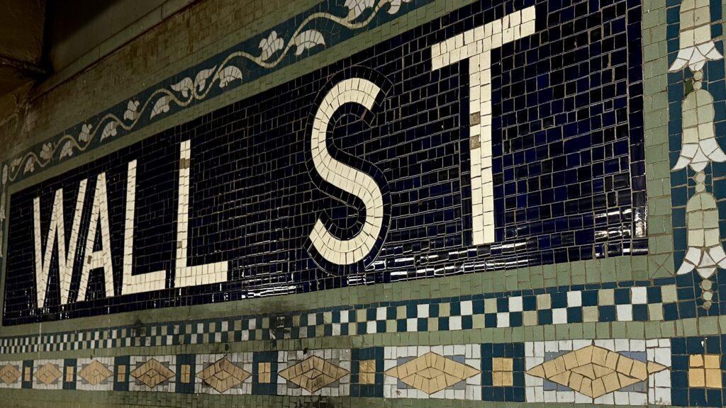 A close-up of the iconic Wall Street subway station sign.