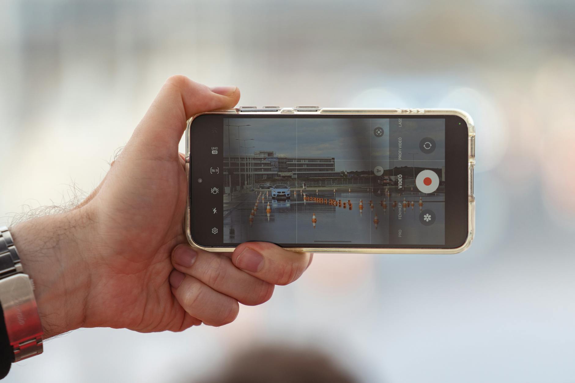 hand holding smartphone and recording video of car