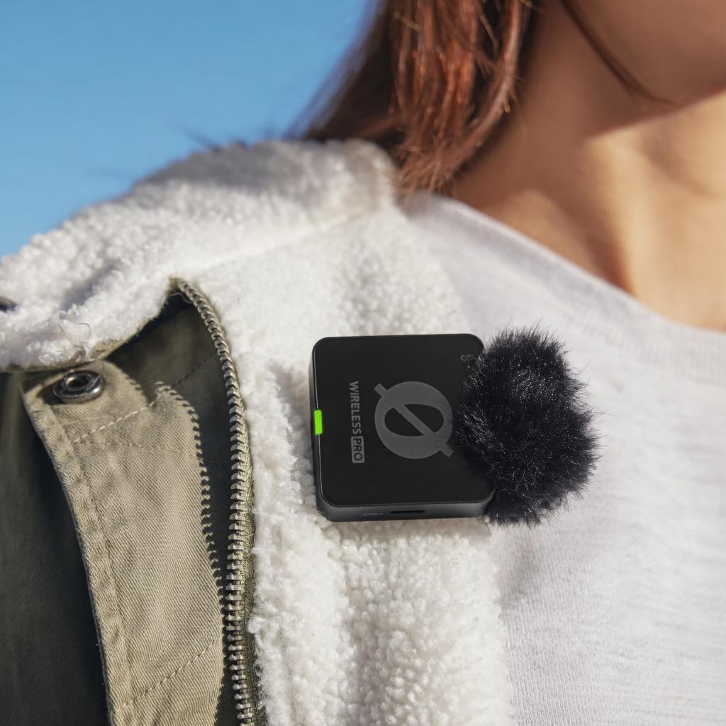 Black Wireless Pro microphone with fuzzy windscreen clipped to a white fleece jacket, with overlay text 'PERFECT AUDIO EVERY TIME WITH GAINASSIST'."