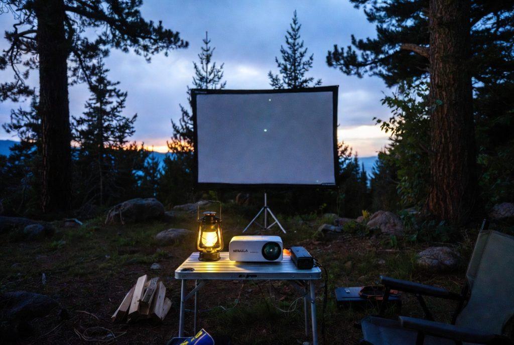 Nebula Mars 3 Air projector setup on camp table at Goldstream Provincial Park campsite movie night, twilight sky in background.