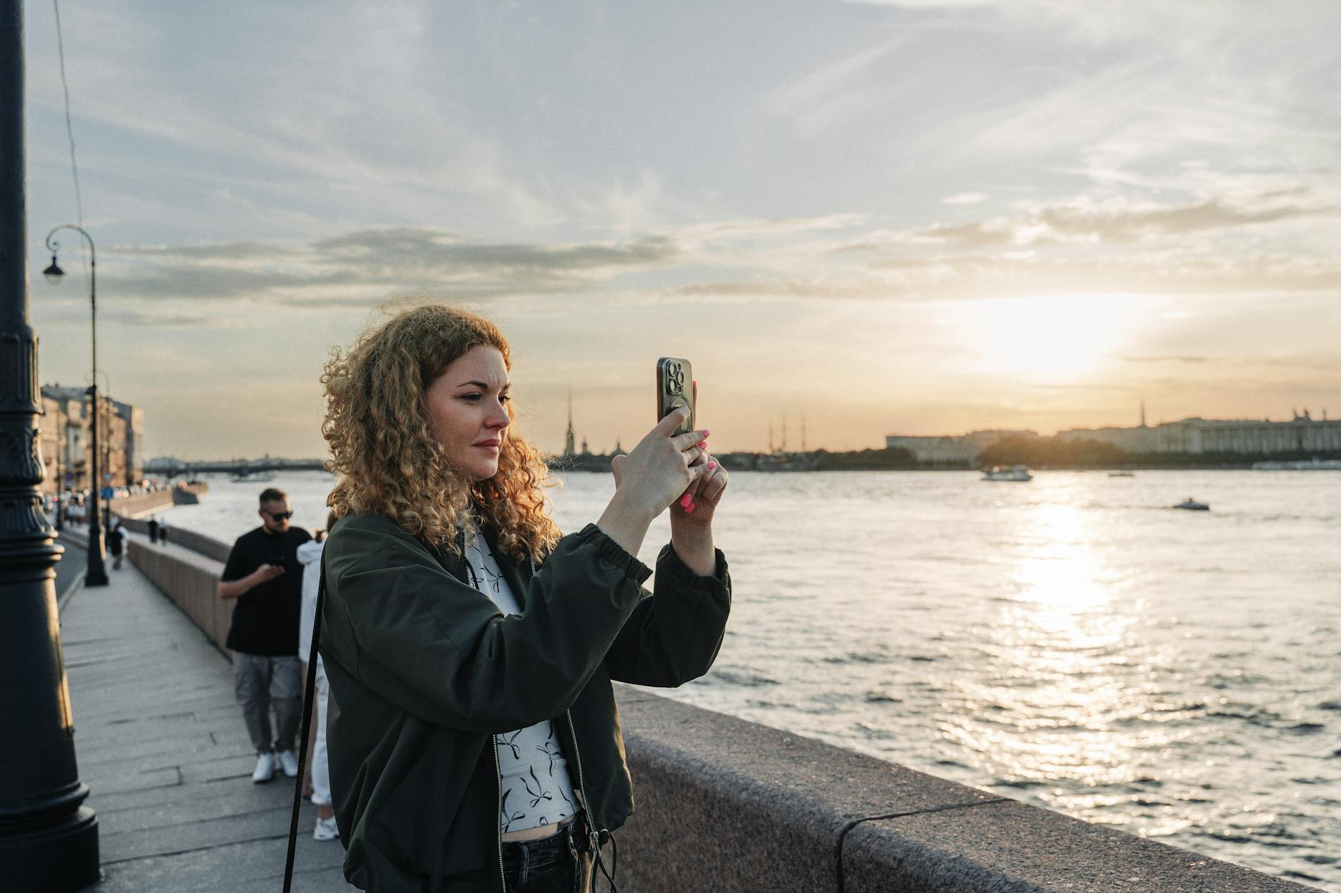 woman taking sunset photo by riverside