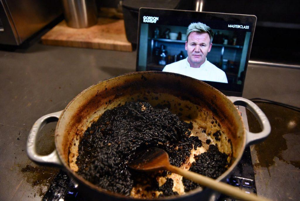 Burned risotto stuck to pot next to laptop showing Gordon Ramsay MasterClass cooking lesson