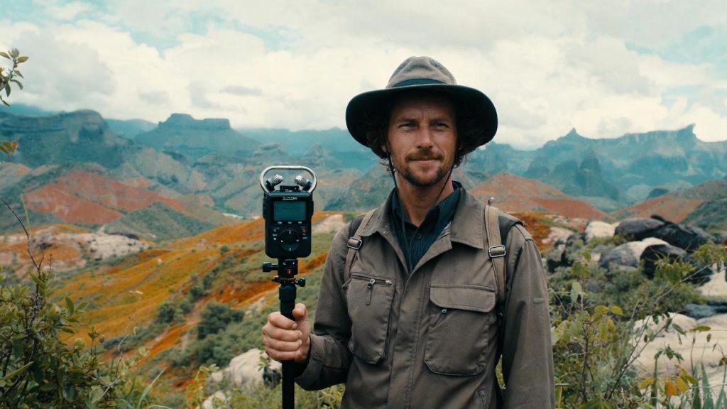 Travel filmmaker capturing spatial audio with ambisonic microphone in authentic mountain location