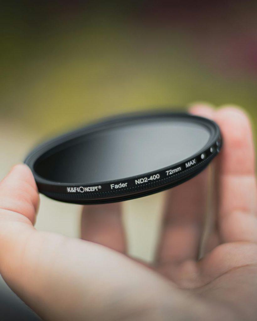 close up of a person holding a camera lens filter