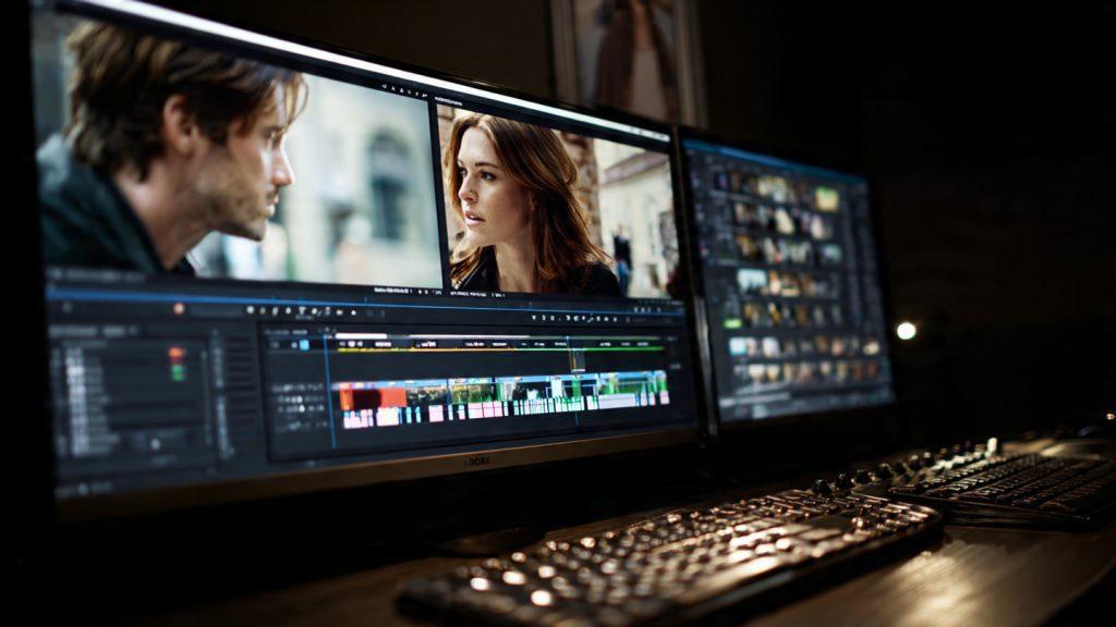 A close-up of a high-end film editing suite in a dark room. The monitor shows a dual-screen setup: one side is a wide shot of two people talking, the other is a haunting close-up of a silent reaction. On the timeline below, several audio clips of dialogue have been muted or deleted, leaving large gaps of silence. The glow from the monitor reflects off a professional editing keyboard. Sleek, modern, "Elsa" short film aesthetic, 8k resolution, cinematic post-production atmosphere. --ar 16:9